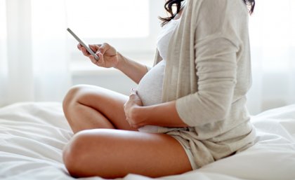 A pregnant woman uses a mobile phone.